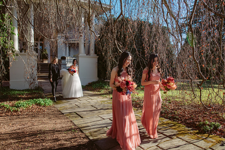 The bride and her bridesmaids walk down the path away from Milton Park hotel towards the ceremony on the Tulip Lawn.
