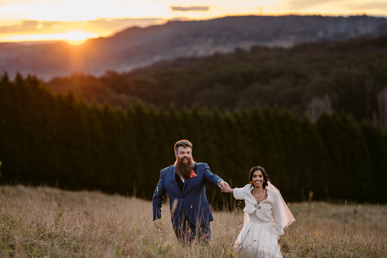 Couple run through an open field at Sunset near the Baillieu Ballroom.