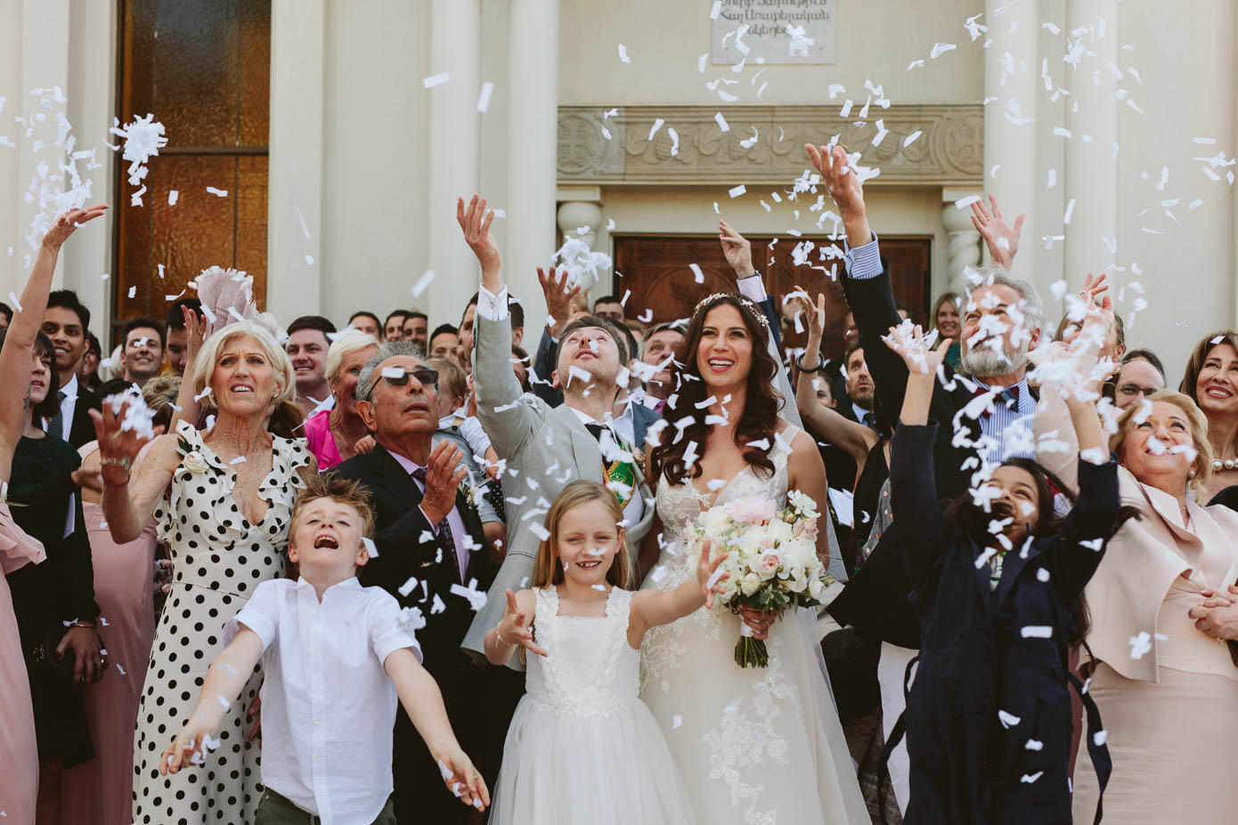 The couple is surrounded by smiling friends and family as they celebrate with a confetti toss.