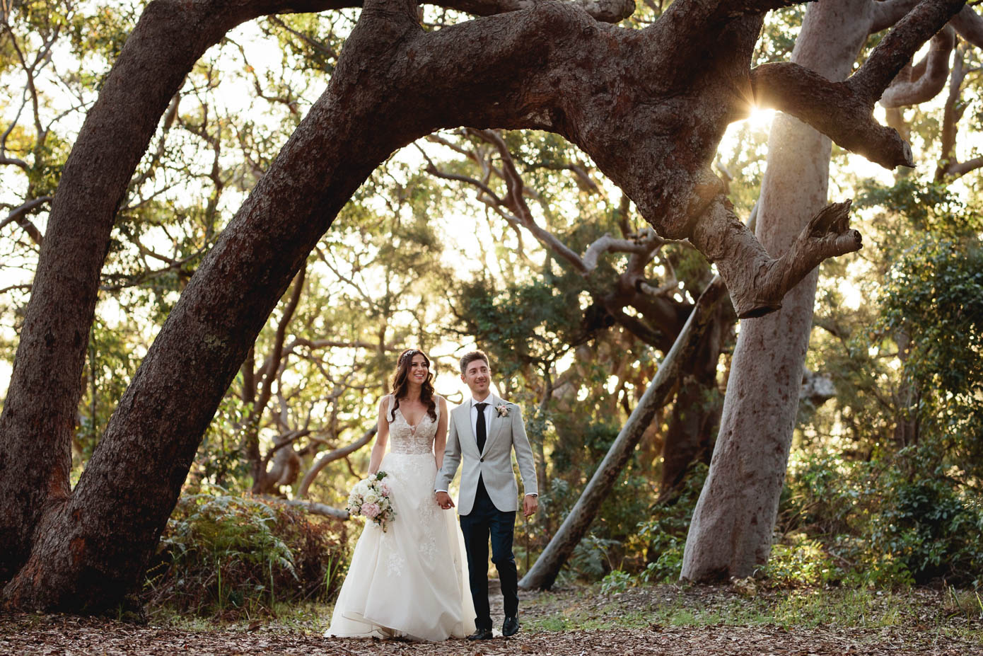 A dreamy outdoor portrait of the couple standing beneath ancient twisting trees.