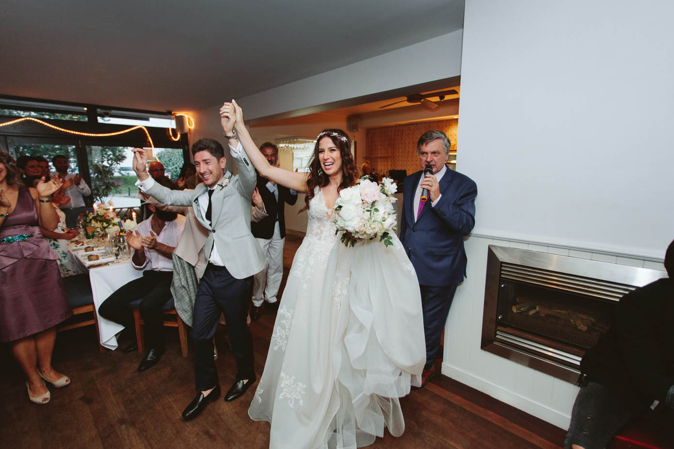 The bride makes a grand entrance into the reception, lifted high in celebration by cheering guests.