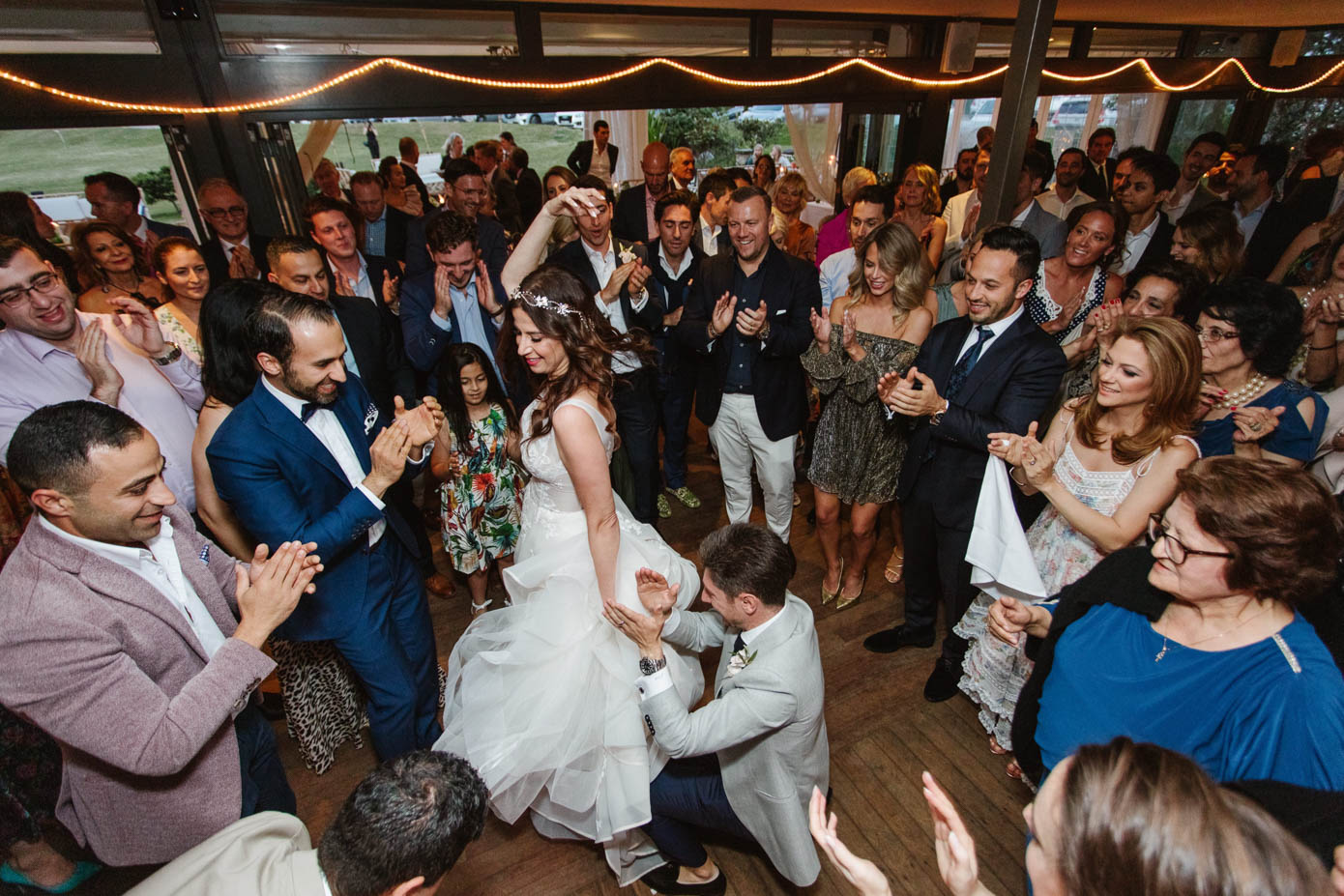 The dance floor comes alive as guests celebrate, clapping and cheering for the newlyweds.