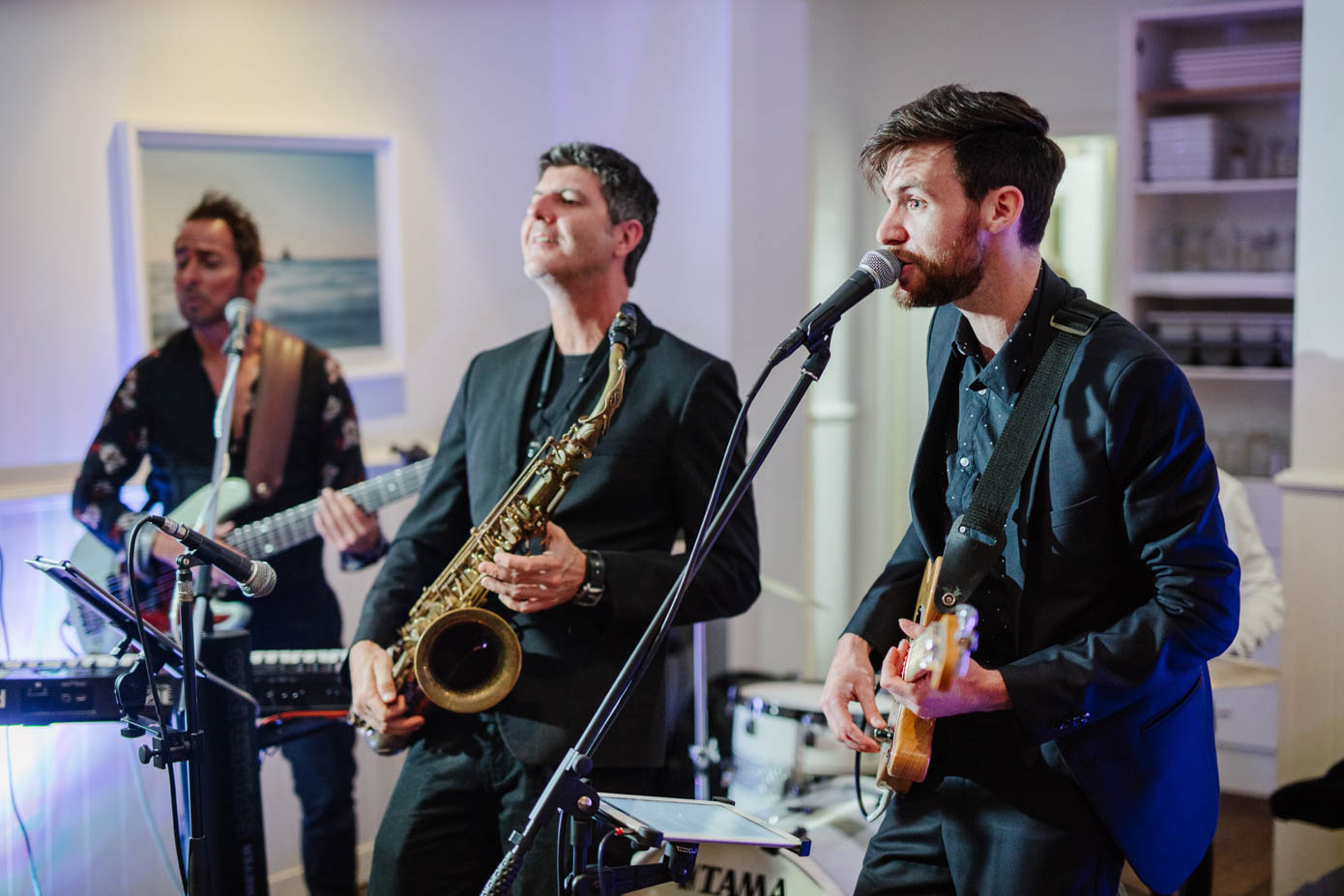 A live band energizes the wedding reception with saxophone and guitar performances.