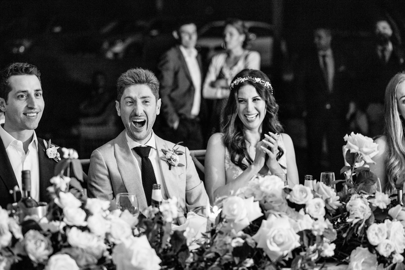A black-and-white capture of guests reacting to a lively and humorous wedding speech.